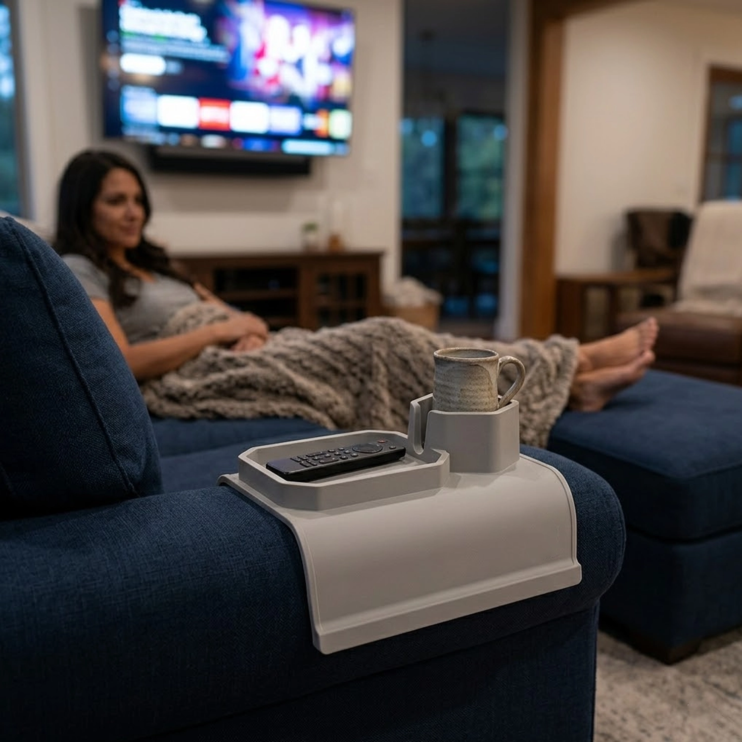 Sofa Sidekick on a deep navy sectional, holding a stoneware mug at dusk